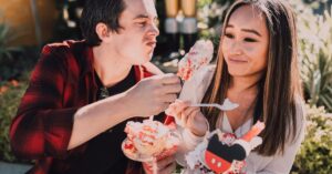 A young couple enjoying colorful desserts on a sunny day outdoors, sharing laughter.